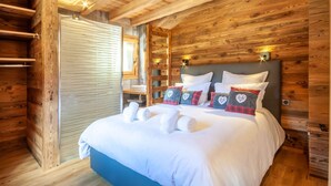 Une chambre dans une cabane en bois, avec un lit, des oreillers et une table de chevet.