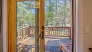 A wooden door leading to an outdoor deck with a metal railing, a bench, and a table. - Ski-in/Out 1st on Mountain Lux Suite + Kitchenette (Bretton Woods)
