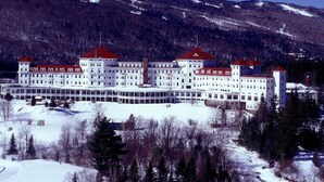 A large, multi-story building with a symmetrical facade, multiple red-roofed sections, and a central courtyard. - Ski-in/Out 1st on Mountain Lux Suite + Kitchenette (Bretton Woods)