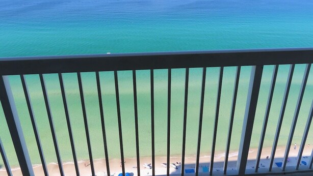 A balcony with a view of the ocean and a beach.