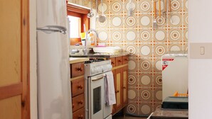 Une cuisine avec des meubles de rangement en bois, un réfrigérateur, un four et un crédence décorée.