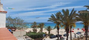 Ein Strand mit Palmen, klarem Himmel und Blick auf das Meer.