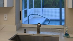 A bathroom with a sink, a window, and a 'RE/MAX' sign above it. - Heated pool for Your next vacation getaway! (North Port)