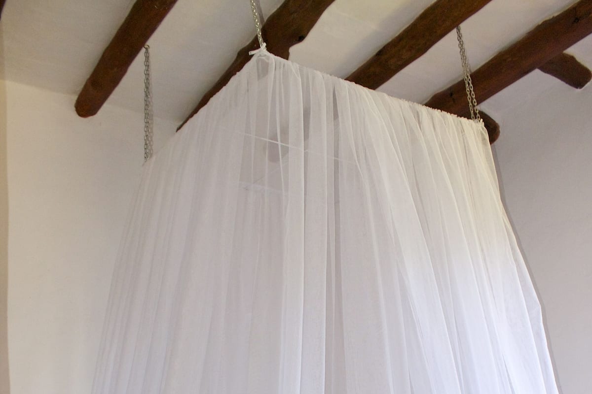 A bed with a white canopy and patterned bedding.