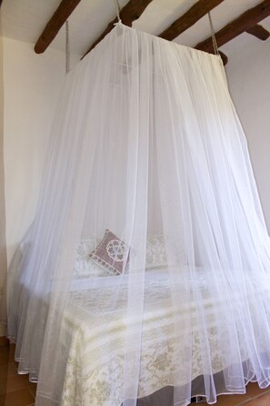A bed with a white canopy and patterned bedding. - La Buganvilla Barichara (Barichara)