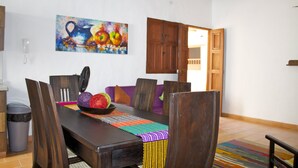 A dining area with a wooden table, chairs, and a colorful woven placemat. - La Buganvilla Barichara (Barichara)