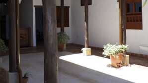 A covered courtyard with wooden beams, potted plants, and a brick floor. - La Buganvilla Barichara (Barichara)