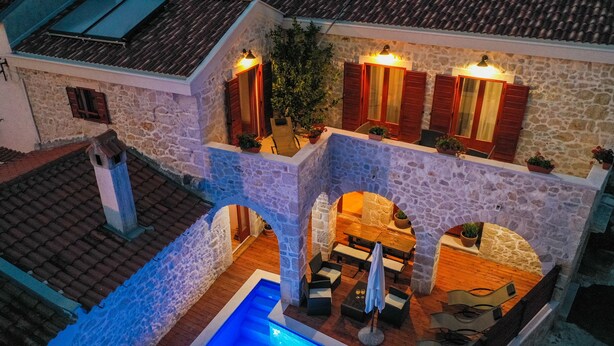 A stone building with a pool, outdoor seating, and wooden shutters. - Holiday home Mare (Petrcane)