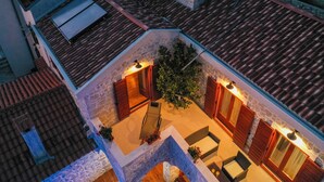 An aerial view of a rooftop terrace with a stone wall, wooden shutters, and a seating area with cushions and a table. - Holiday home Mare (Petrcane)