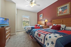 A bedroom with two beds, a ceiling fan, a TV, and a window with blinds. - 3 BD/ 2 BA/ Lucaya Village (1-102) (Kissimmee)