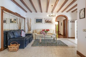 A living room with a sofa, a coffee table, and a rug. There are pictures on the wall and a chandelier.