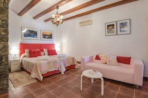Un dormitorio con cama, sofá, mesita de noche, lámpara y candelabro.