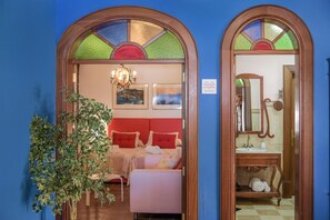 A hotel room with a bed, a bedside table, a mirror, and a wall-mounted chandelier.