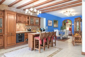 Una cocina con armarios de madera, una isla central y un comedor con sillas.