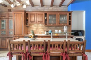 A kitchen with wooden cabinets, a central island with chairs, and a microwave. - Beachfront Ground-Floor Villa w/ Pool & BBQ (Playa Honda)