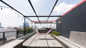 Une terrasse sur le toit avec un hamac, une vue sur la ville et une rambarde en verre.