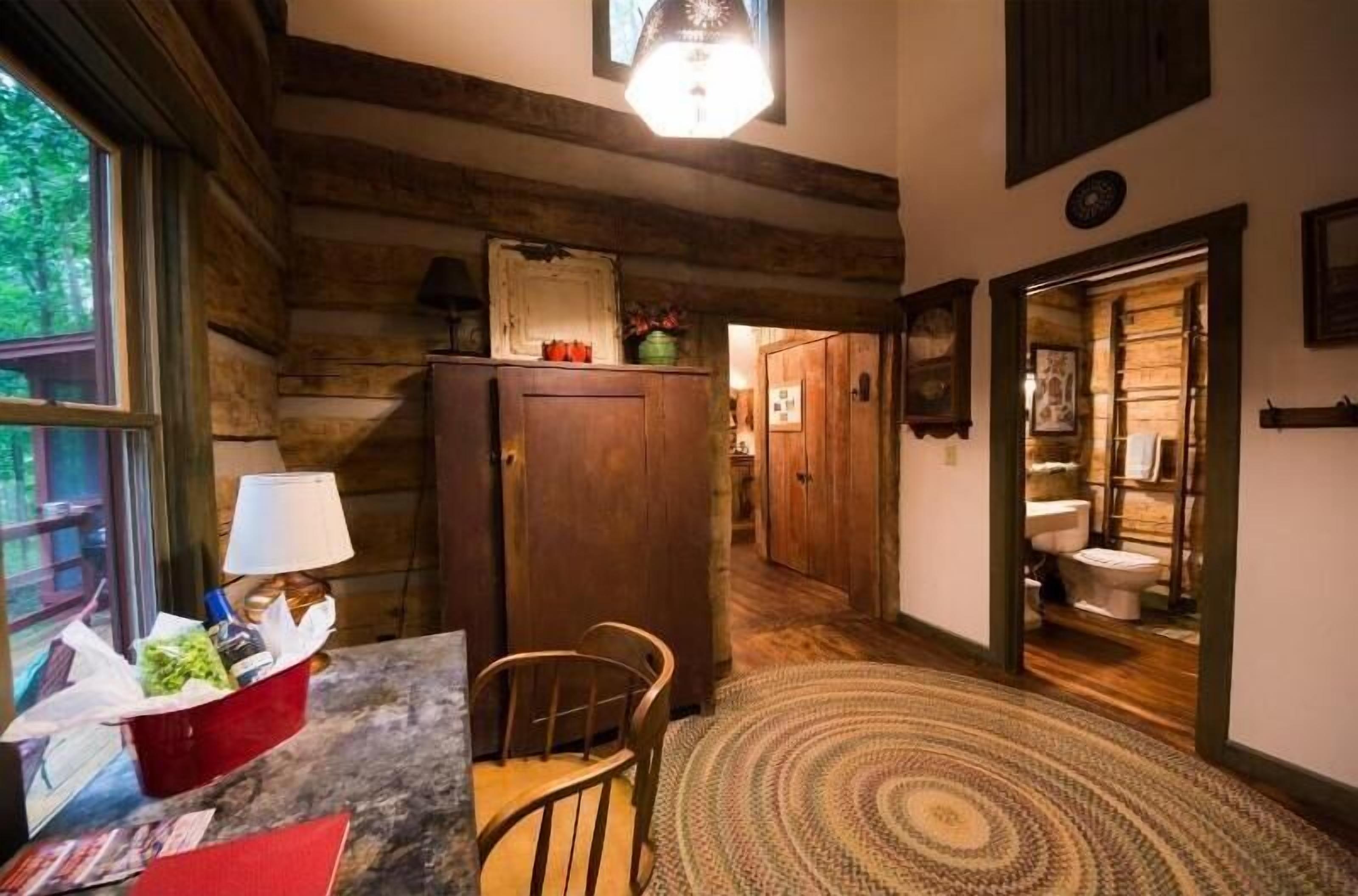 Un interior de madera con cocina, una mesa de comedor con sillas y un pasillo que lleva a un baño.