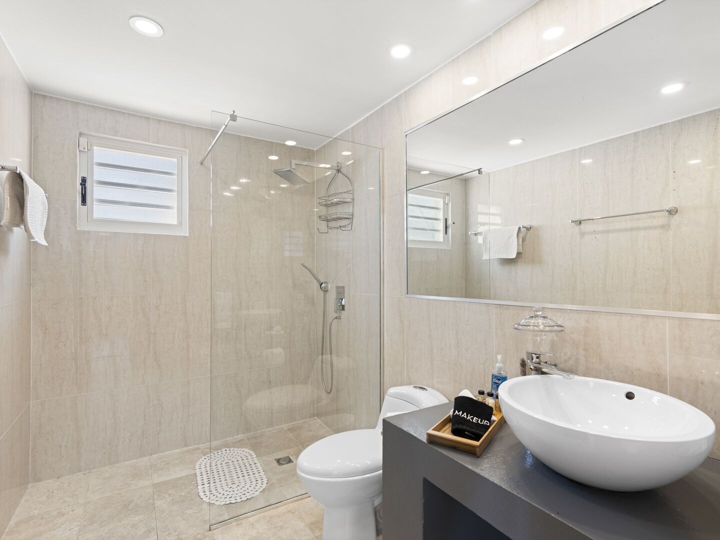 A modern bathroom with a glass-enclosed shower, a white toilet, and a vanity with a large sink.