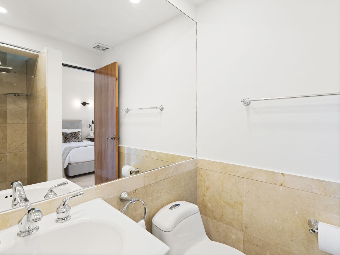 Une salle de bain moderne avec un grand miroir, un lavabo, des toilettes et un espace douche.