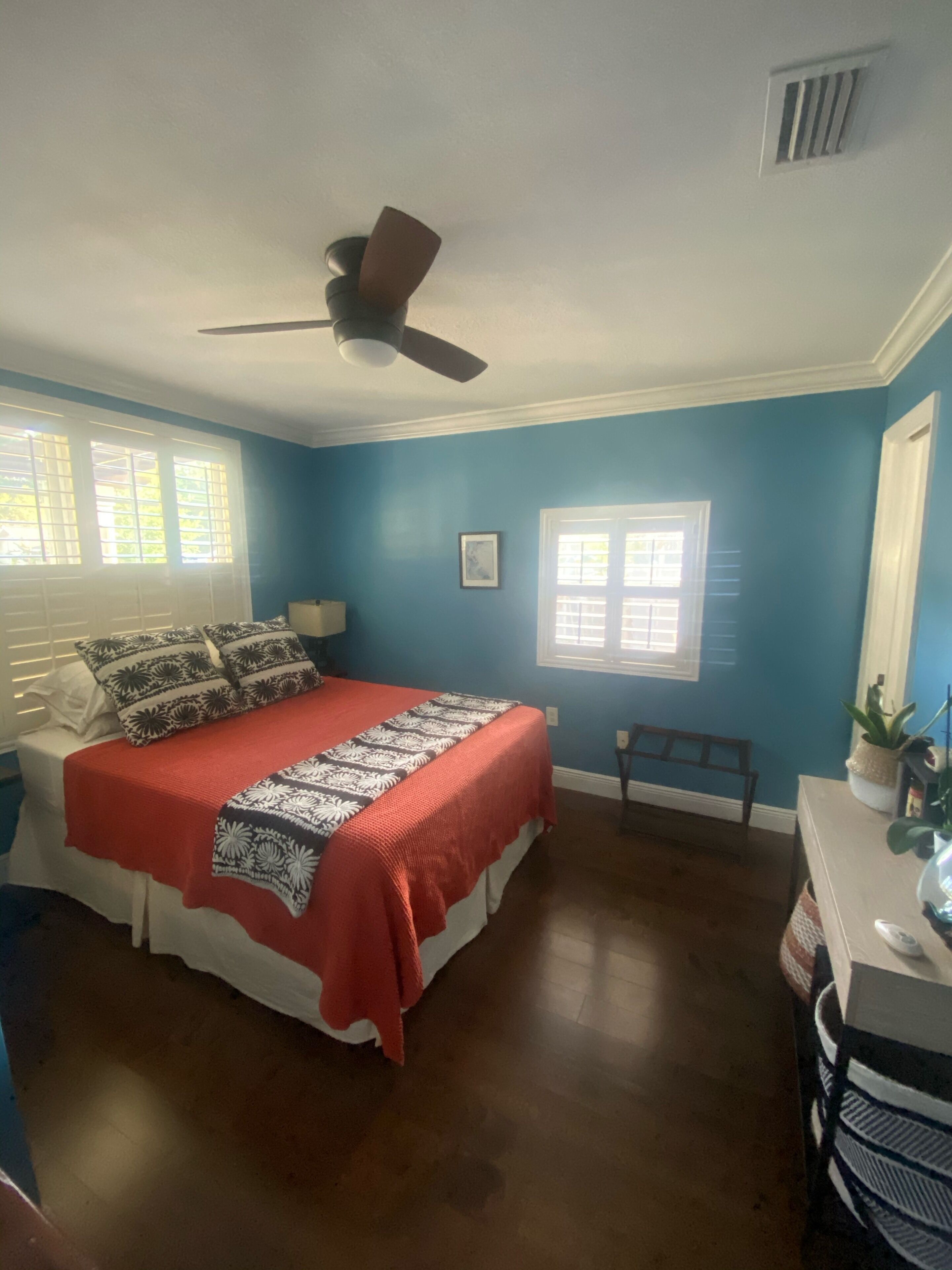A bedroom with a bed, a ceiling fan, a window, and a nightstand.