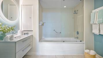 Un baño moderno con una bañera, ducha, tocador con espejo y una cesta de mimbre con toallas.