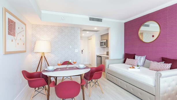 A modern bedroom with a bed, a round mirror, and a dining area with chairs and a table. - Private Oasis at Arya (Miami)