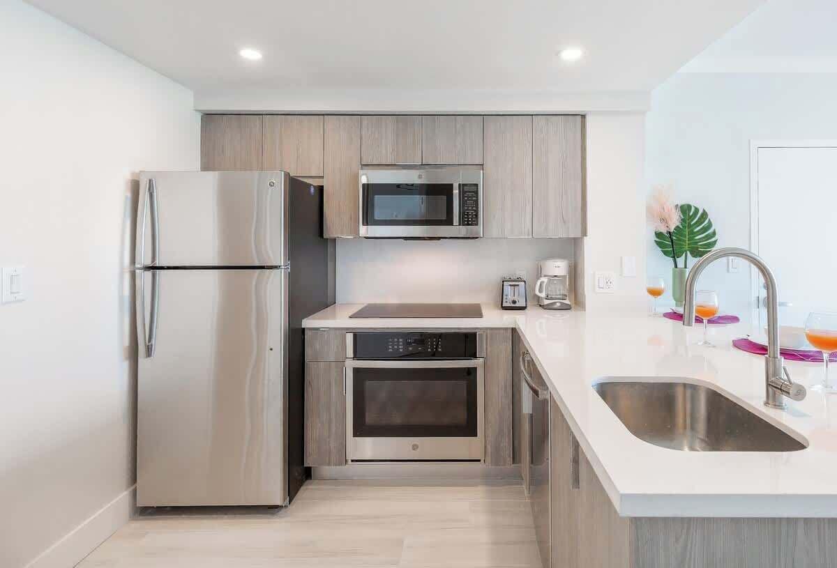 A modern kitchen with a stainless steel refrigerator, microwave, oven, and coffee maker.