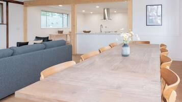 Un espace repas moderne avec une table et des chaises en bois, un canapé gris et un vase de fleurs.