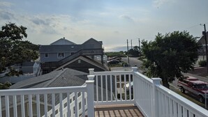 A residential area with a staircase leading to a deck, a house with a gabled roof, and a view of the ocean.