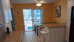 A kitchen with a wooden countertop, a dining area with stools, and a sliding glass door leading to a deck.