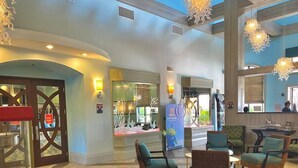 Un hall d’entrée spacieux avec un comptoir d’accueil, des coins salon confortables et un éclairage moderne.
