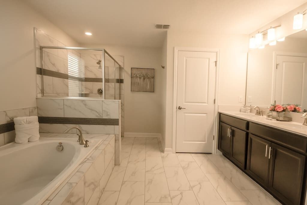 Une salle de bain moderne dotée d’une douche à parois de verre, d’une baignoire sur pieds et d’un meuble-lavabo avec un grand miroir.
