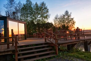 A wooden deck with outdoor seating and a glass building. - Hotel Joseph Conrad (Pisz)