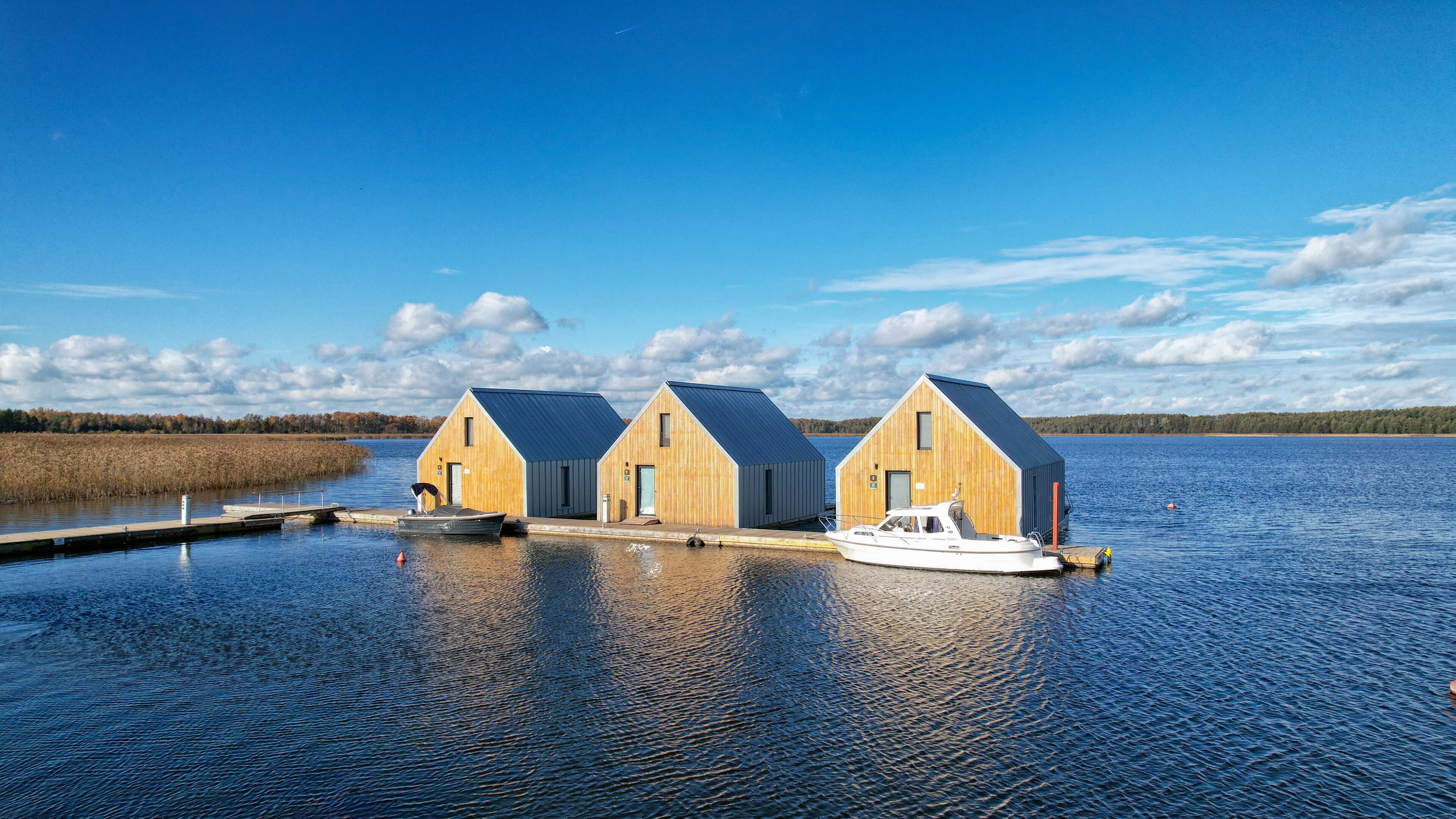 Three wooden buildings with a boat docked in front.
