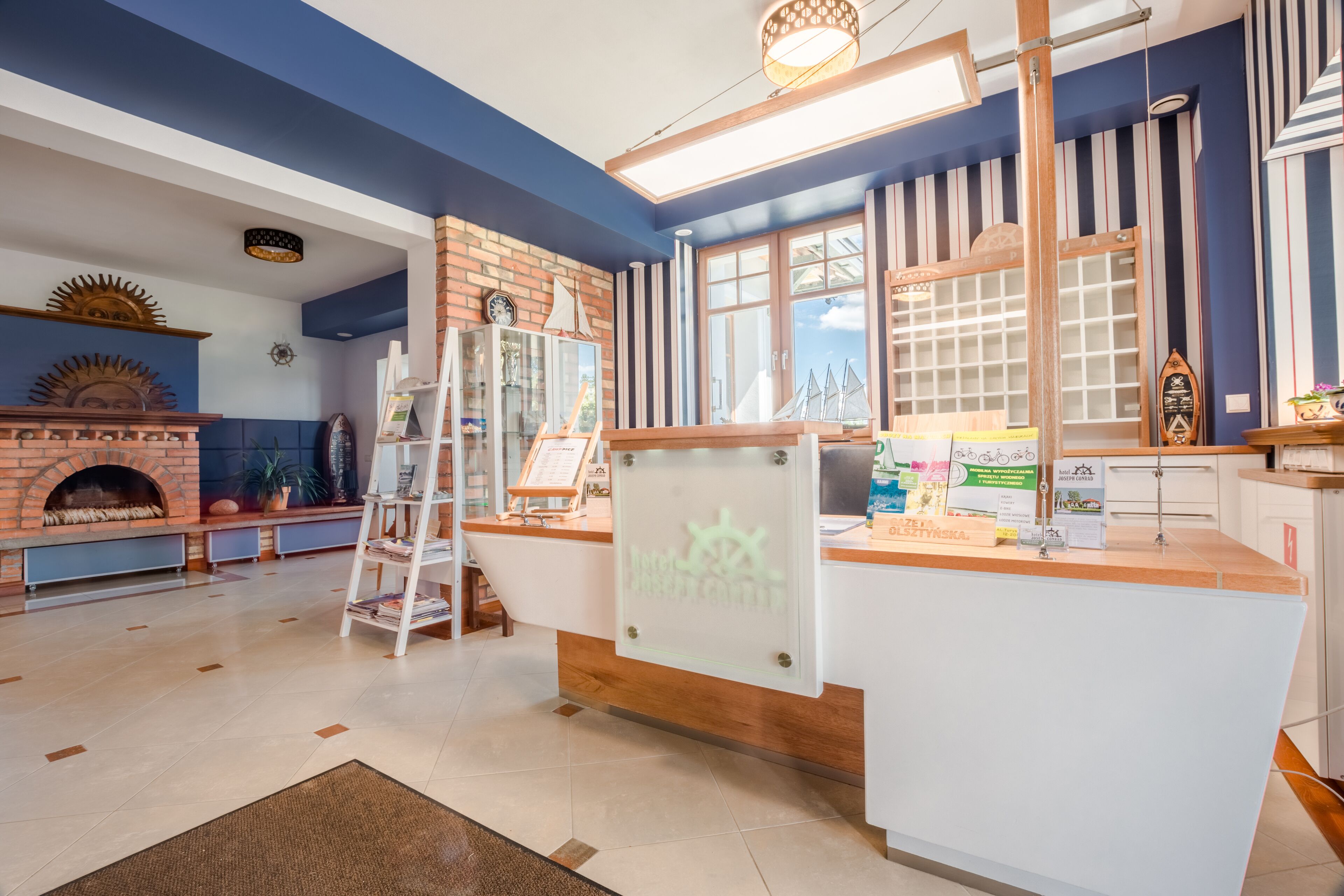 A cozy room with a brick fireplace, a wooden ladder, and a reception desk with a nautical theme.
