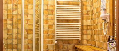 A bathroom with a glass shower enclosure, a white toilet, a wooden vanity with a sink, and a towel rack.