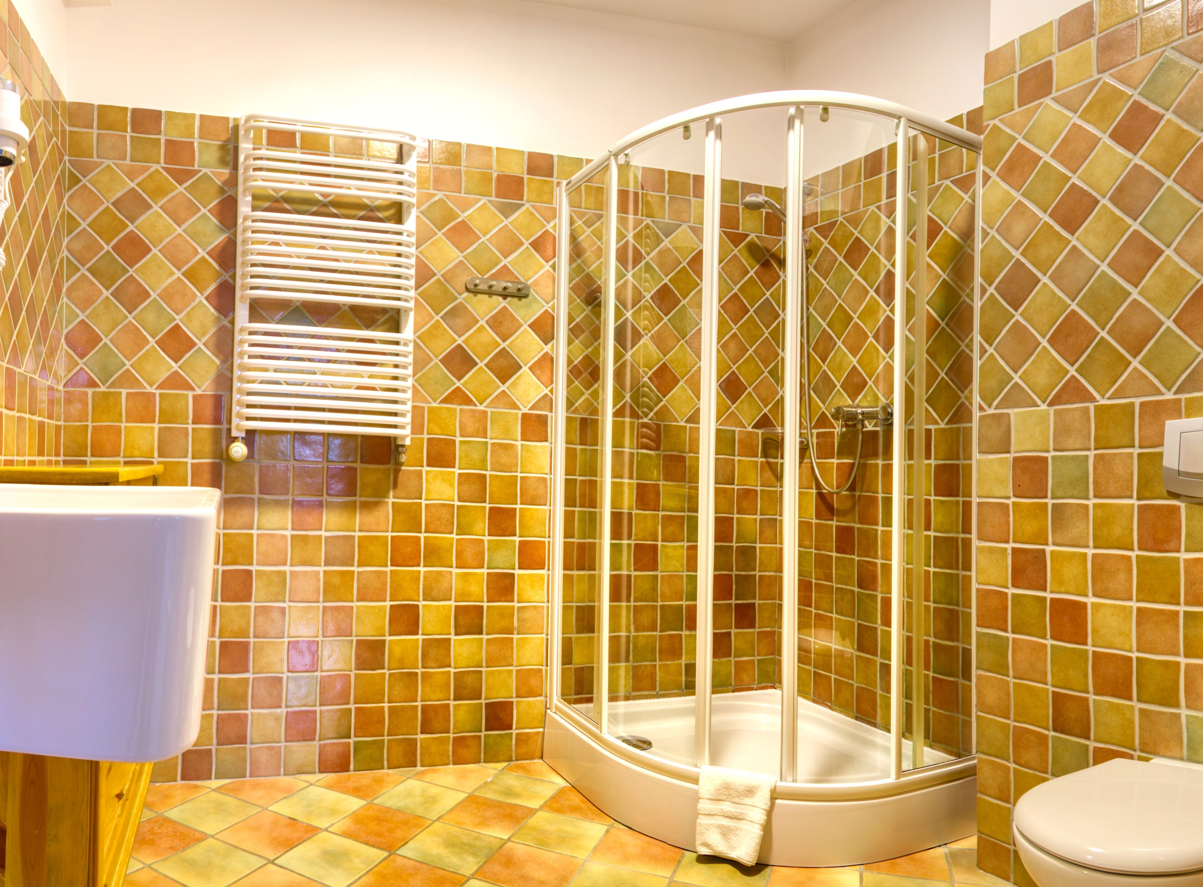 A bathroom with a glass-enclosed shower, a white sink, and a toilet.