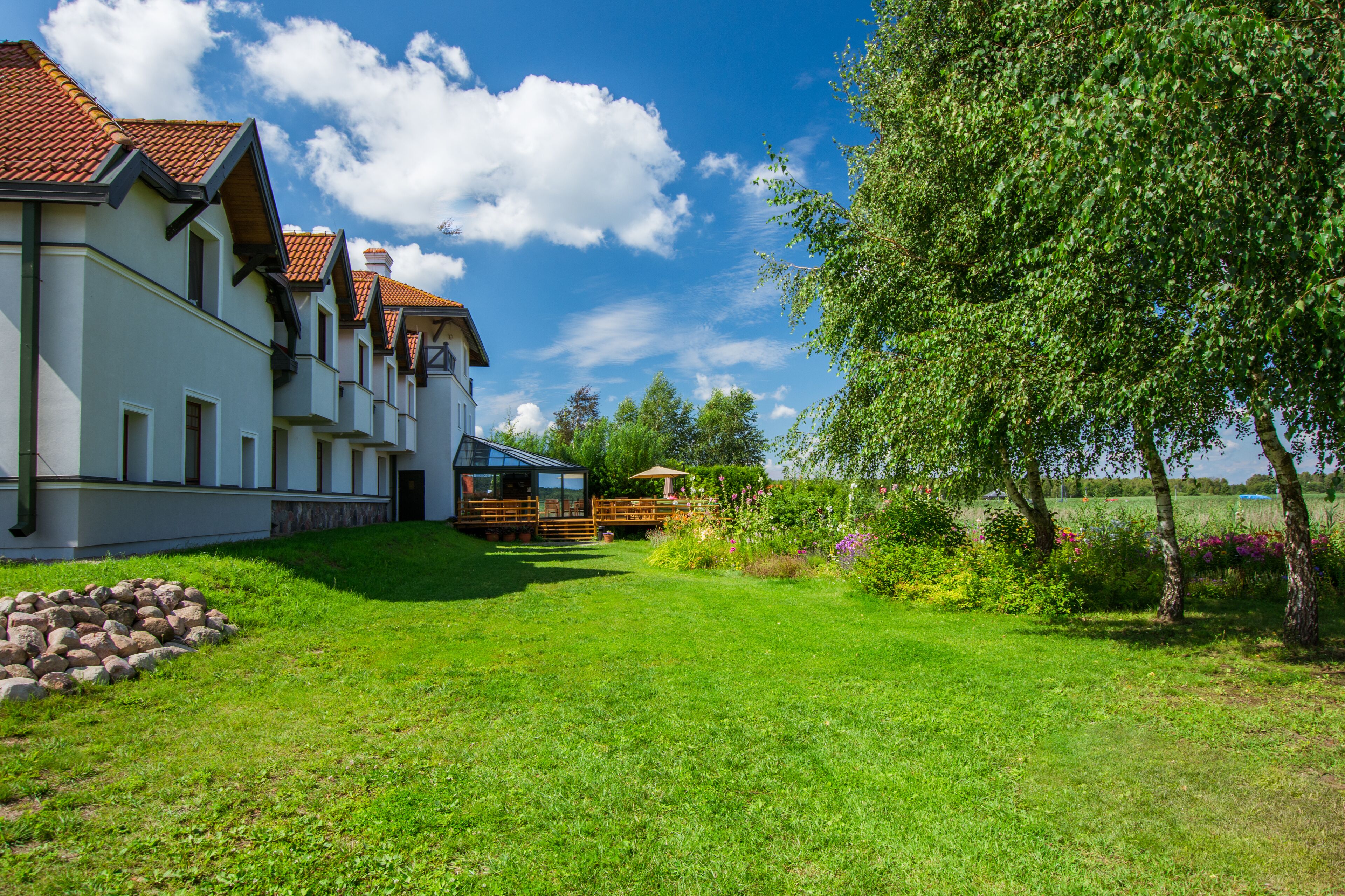 A large house with a sloped roof, a well-maintained lawn, and a wooden fence.