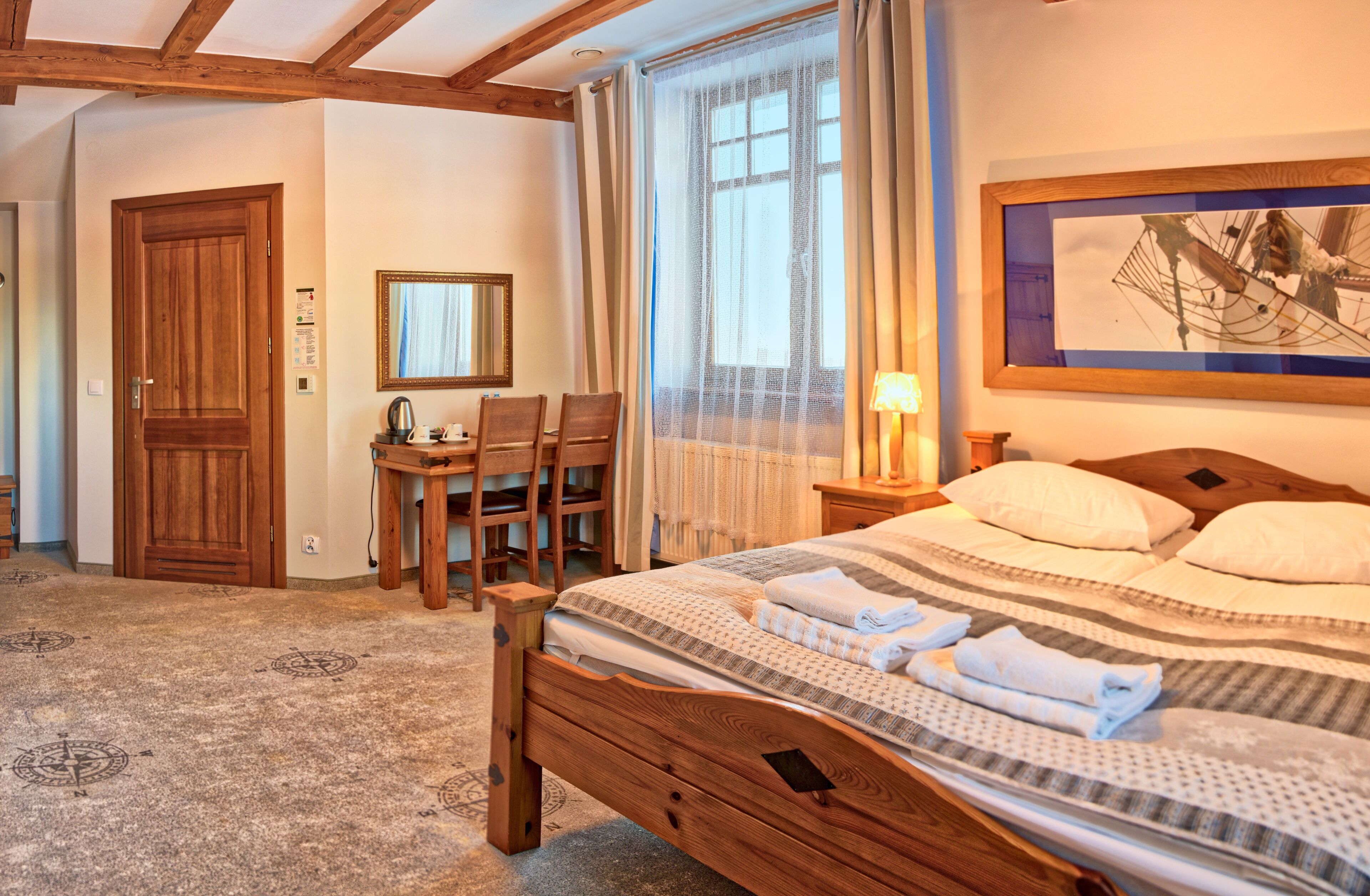 Un dormitorio con una cama de madera, un escritorio con silla, un espejo y una ventana con cortinas.