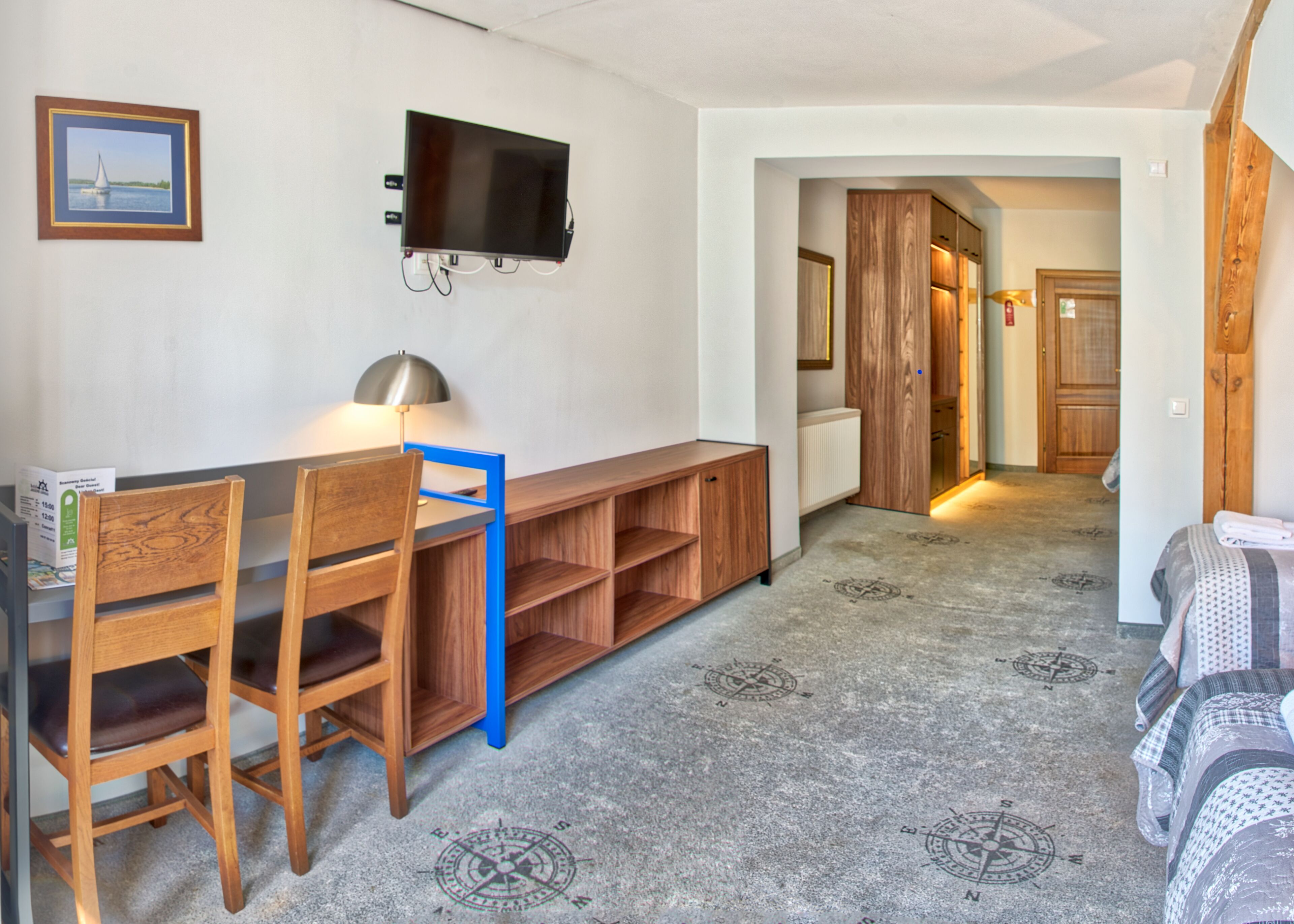 A room with a desk, chairs, a TV, and a bed.