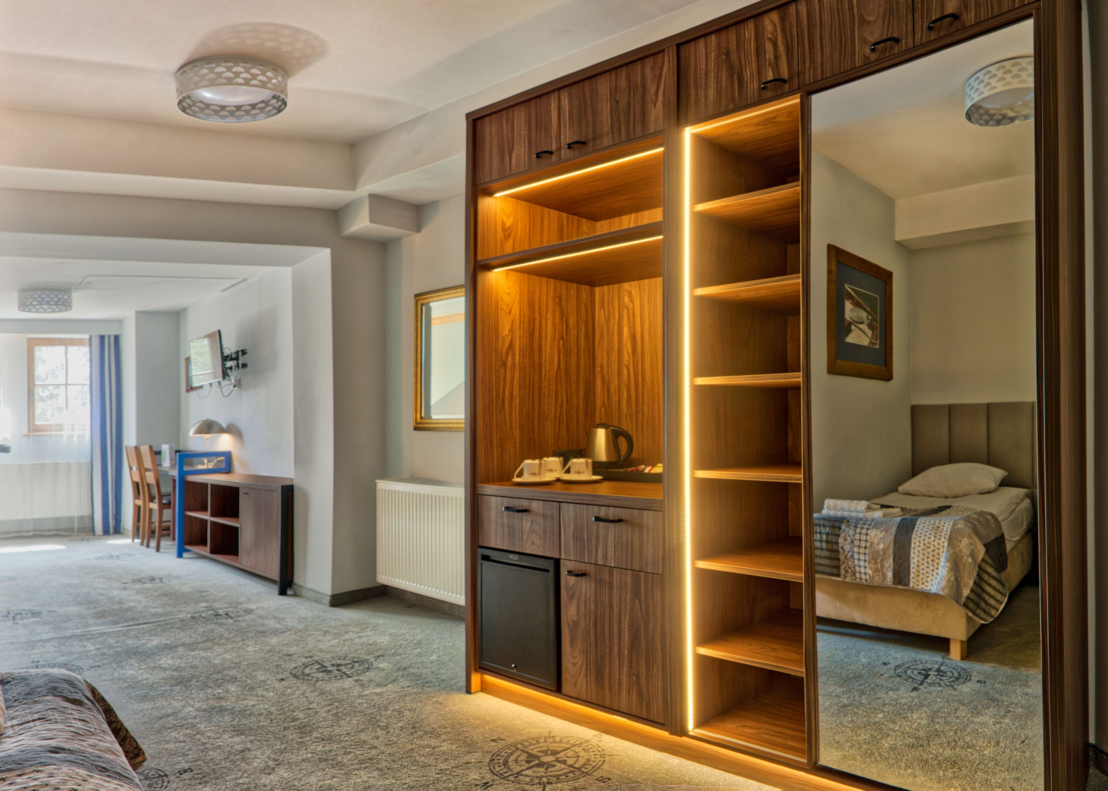 A modern bedroom with a large wardrobe, a bed, and a desk with a lamp.