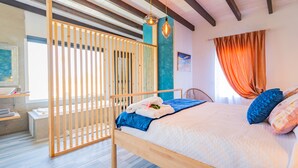 Un dormitorio con cama de madera, vista al baño y ventana con cortinas.