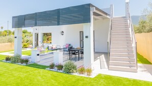 Un patio moderno al aire libre con zona de estar cubierta, una escalera y vistas del paisaje circundante.
