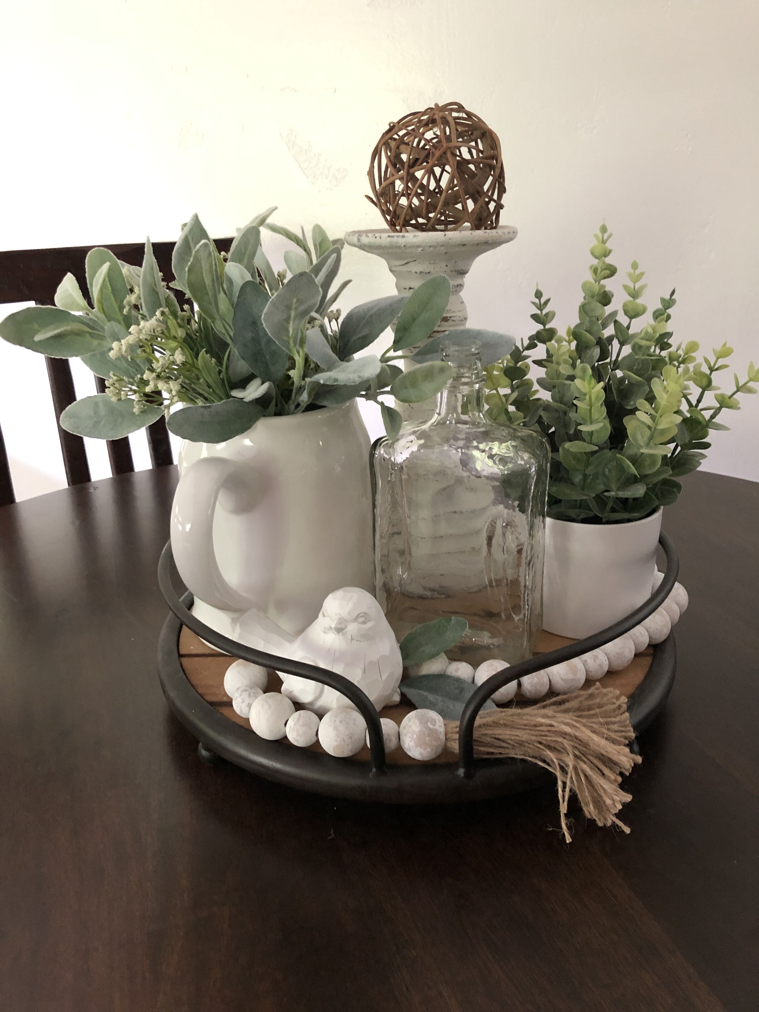 A decorative tray with a ceramic elephant, a glass bottle, and green plants.