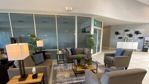 A modern lobby with a curved ceiling, seating area with sofas and armchairs, a coffee table, and a lamp. Large windows provide natural light, and there is a reception desk in the background. - The Encantada Escape – 3BR Townhome w/ Private Pool (Four Corners)