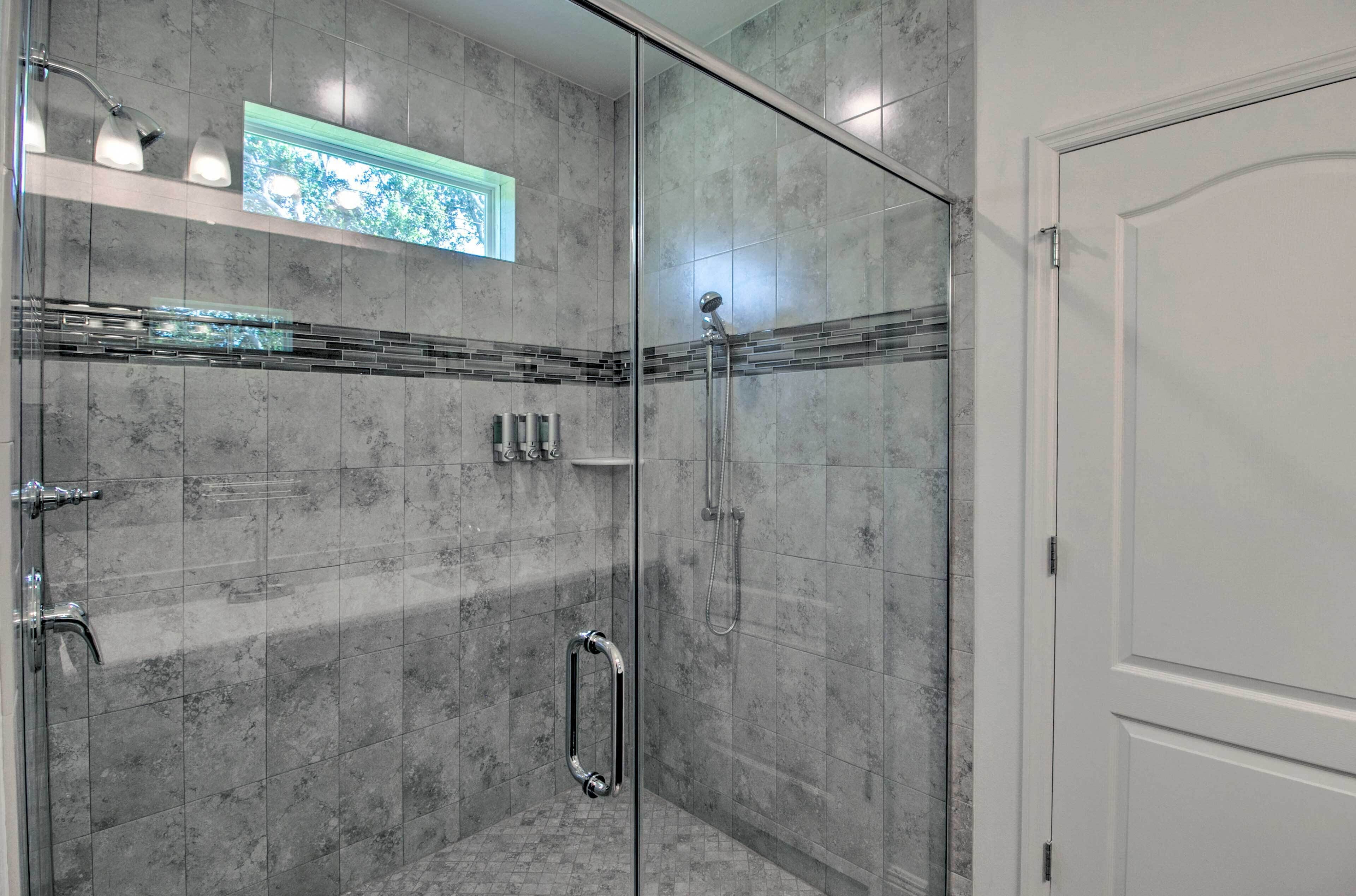 Un baño moderno con cabina de ducha de vidrio, lavabo integrado y un pequeño ventanal con vistas.