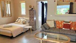 Un dormitorio con cama, cómoda, mesa de centro de vidrio y sofá.