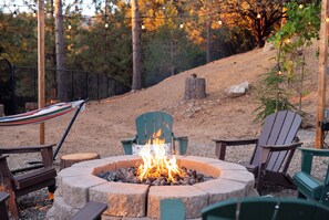 An outdoor seating area with a fire pit, chairs, and a hammock. - Mountain Oasis, Sleeps 24, Hot tub, Game room (Oakhurst)
