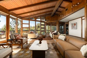 A spacious living area with a high ceiling, large windows, and a view of the outdoors. - Mountain Oasis, Sleeps 24, Hot tub, Game room (Oakhurst)