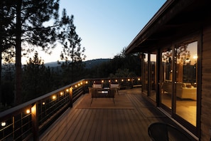 A wooden deck with a seating area, overlooking a forested landscape.
